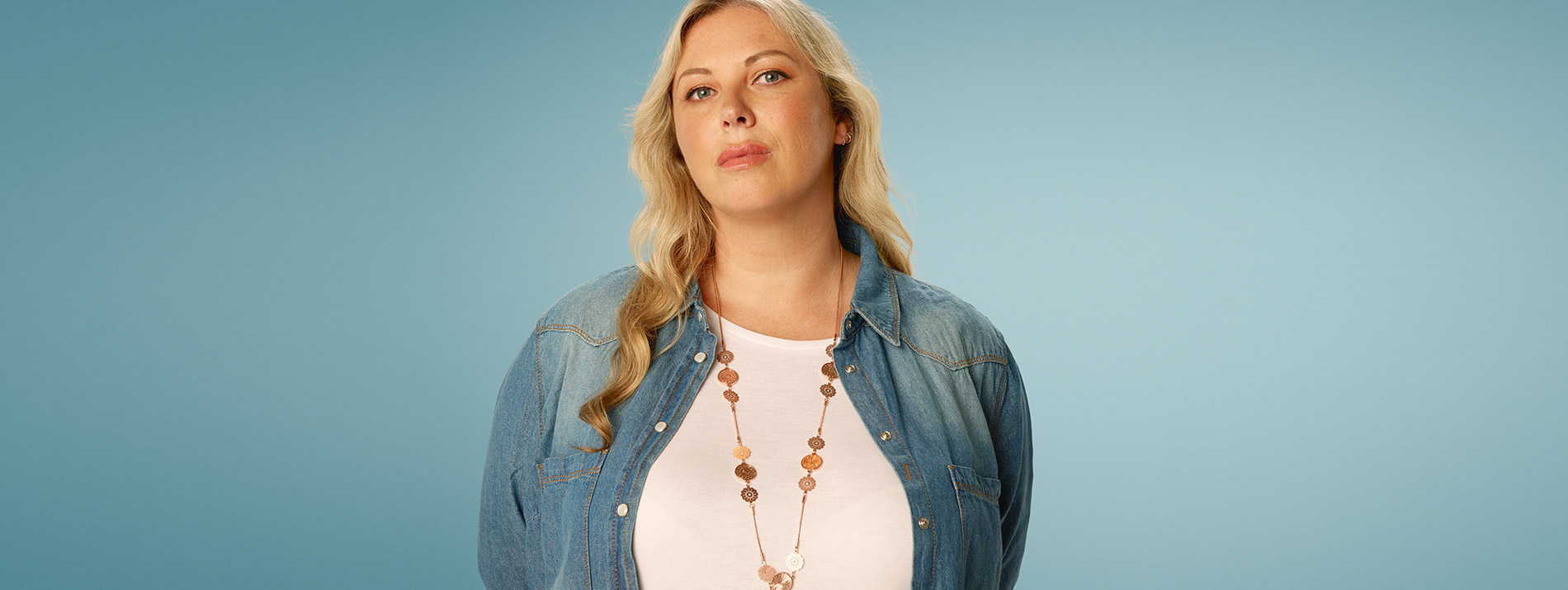 Centered portrait of a confident looking woman in a blue cardigan.
